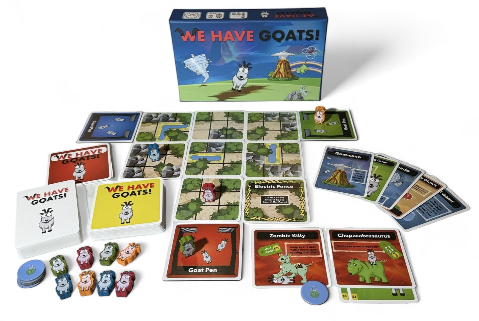 The full We Have Goats game laid out: box, pasture tiles, wooden goat meeples, power cards and action cards